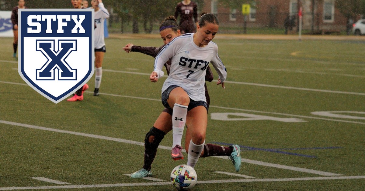 A StFX women's soccer player in white shields the ball from a defender in maroon, with the StFX crest in the corner