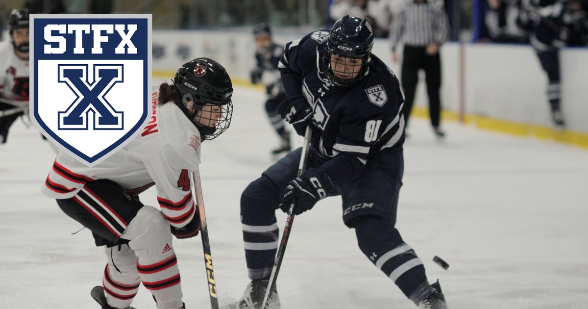 A StFX women's hockey player in navy carries the puck past a defender in white and red, with the StFX crest in the corner