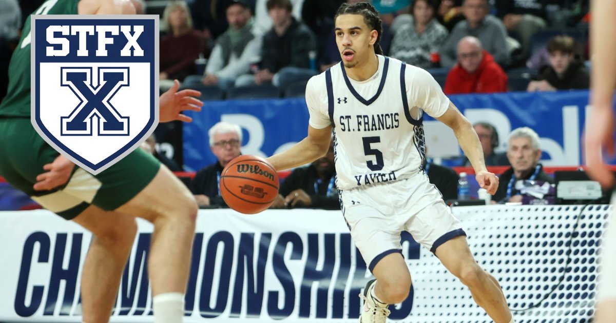 A StFX men's basketball player in a white St. Francis Xavier jersey dribbles past a defender, with the StFX crest in the corner