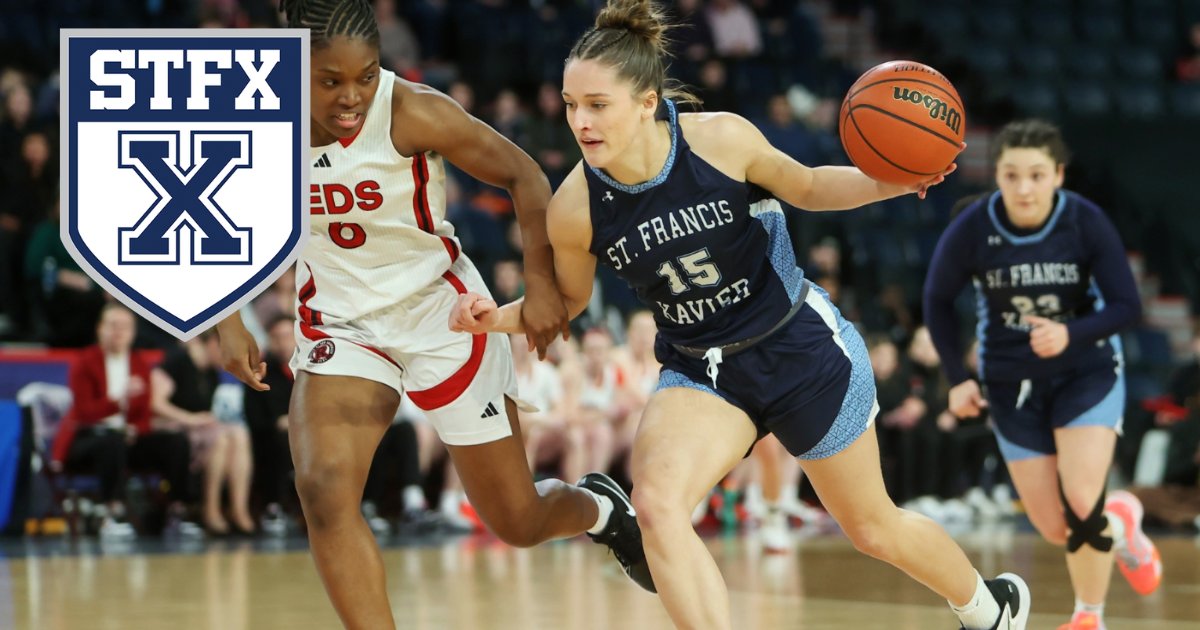 A StFX women's basketball player in navy drives past a defender in red and white, with the StFX crest in the corner